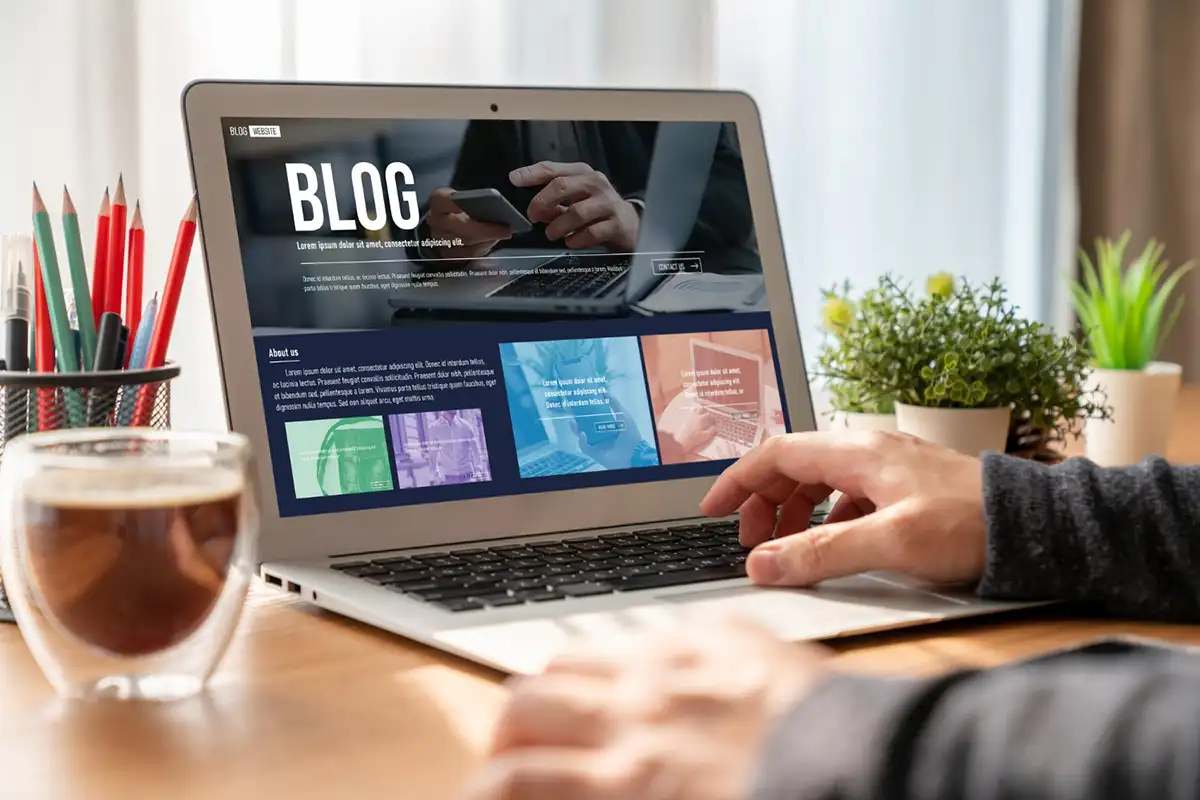 Empresário trabalhando no notebook em um blog para empresa, com café e plantas na mesa
